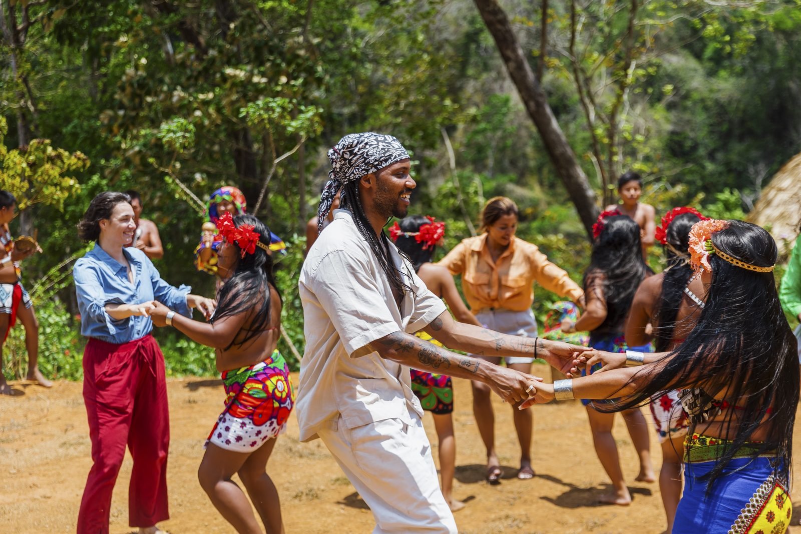 Visitantes bailan tomados de la mano con mujeres y hombres emberá en su comunidad junto al río Chagres