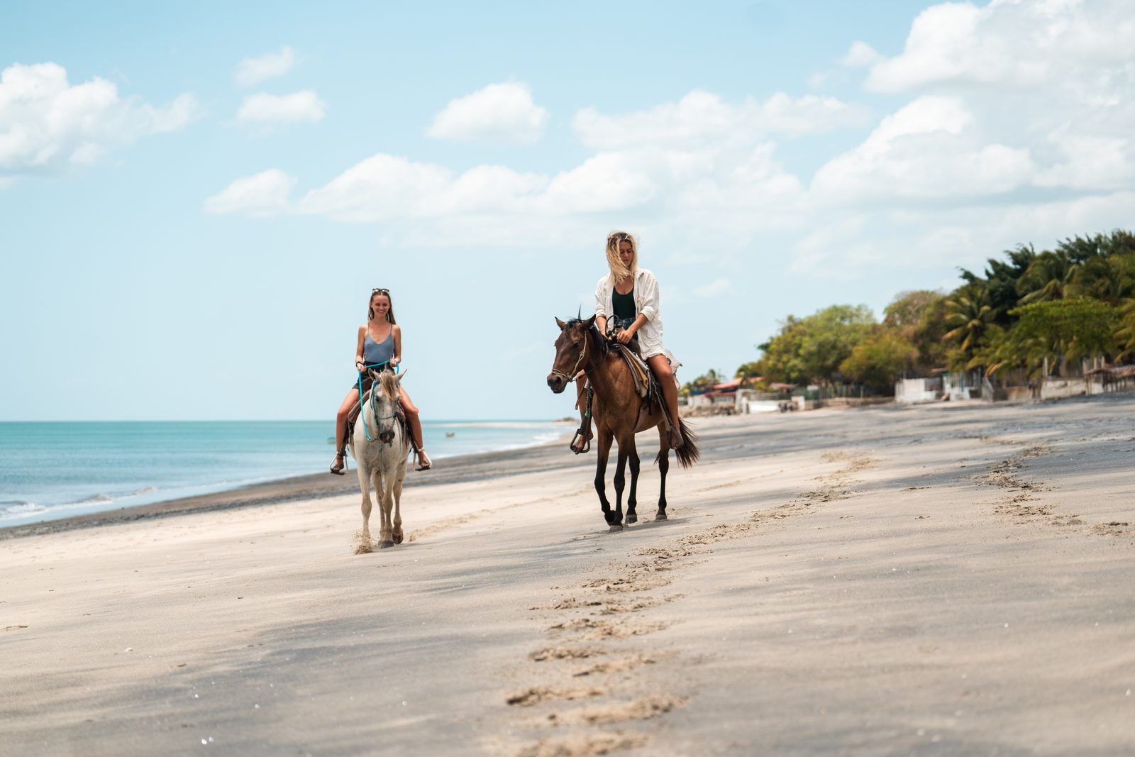 Dos amigas cabalgan por la playa de Farallón con el mar tranquilo al lado