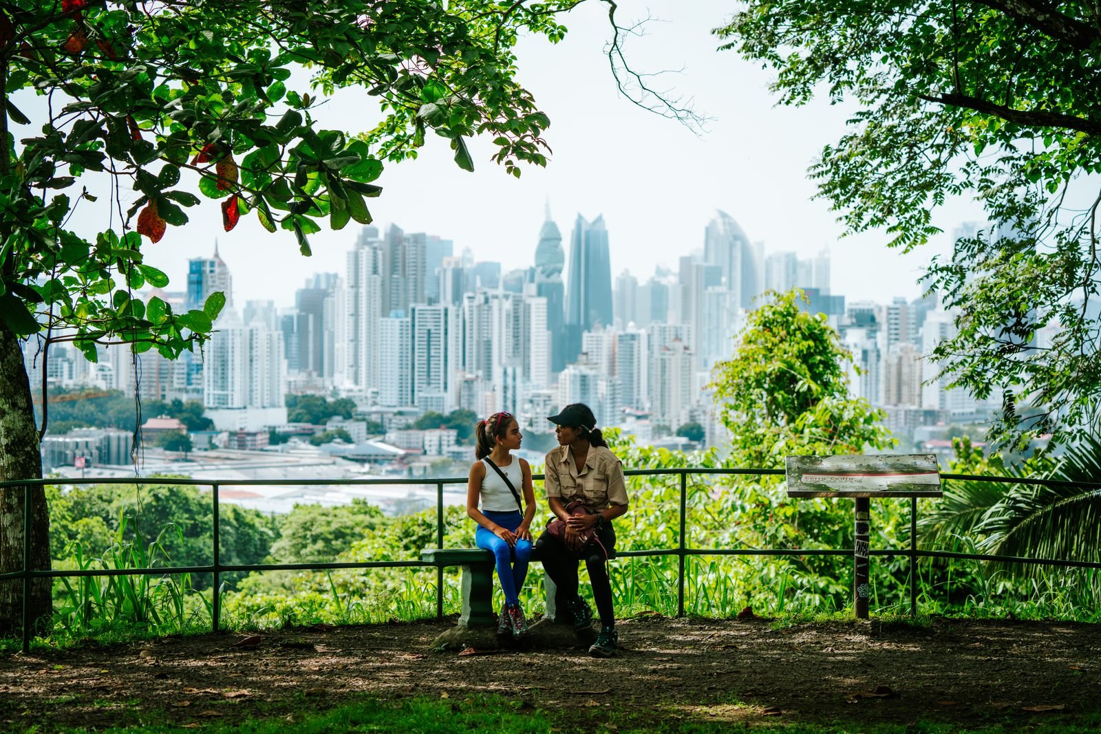 Dos personas en el mirador del Parque Natural Metropolitano, con los rascacielos detrás de los árboles