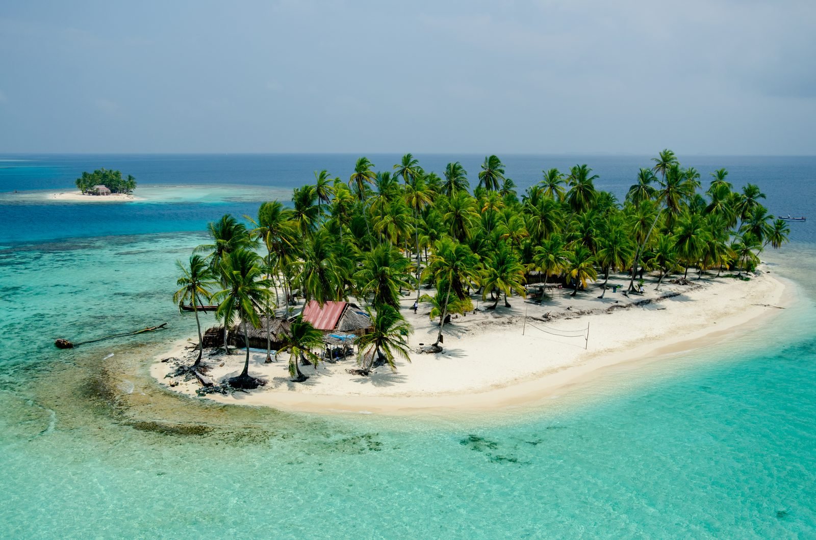 Una isla de San Blas vista desde arriba, con palmeras, cabañas y arena blanca rodeada de agua turquesa